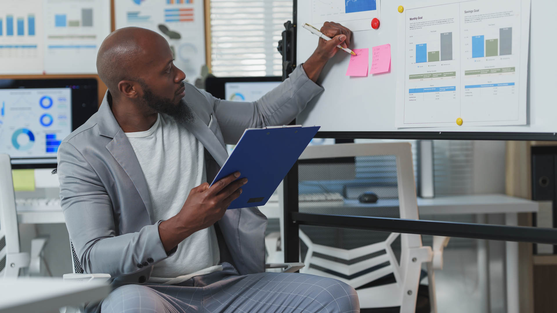 Man reviewing charts and notes on a board with graphs and sticky notes.
